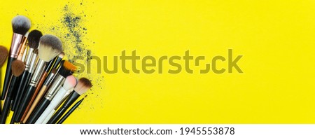 Make up the essentials. A set of professional makeup brushes and cosmetics on a yellow background. Space for your text or logo. Perfect for a beauty blog. Flatly, horizontal. Banner. Copy space.
