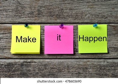 MAKE IT HAPPEN text written on sticky note on wooden background. Motivational quotes