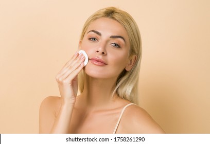 Make up remover. Beautiful woman with a sponge and micellar water. Skin care and beauty. Young beautiful woman cleaning her face