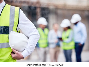 Make safety a priority. Shot of an unrecognizable architect holding a helmet at a building site.
