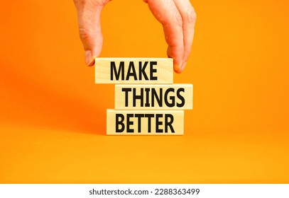 Make things better symbol. Concept words Make things better on wooden block on a beautiful orange table orange background. Businessman hand. Business and make things better concept. Copy space.