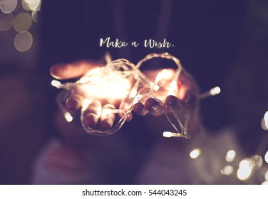 Make a wish word over hand with light bokeh in vintage filter,Holiday quote,christmas season - Powered by Shutterstock