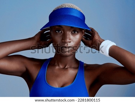 I make a workout look good. Studio shot of a sporty young woman wearing a visor while posing against a blue background.