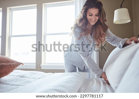 Make your bed then make things happen. a beautiful young woman making her bed in the morning at home.