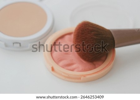 Makeup application with blush and brush on a clean surface