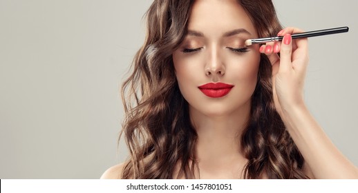  Makeup artist applies  eye shadow  . Beautiful woman face. Hand of visagiste, painting  cosmetics of young beauty  model girl . Make up in process - Shutterstock ID 1457801051