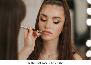 Makeup artist applies lipstick. Hand of make-up master, painting lips of young beauty redhead model. Make up in process. Close-up view - Powered by Shutterstock