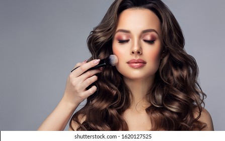Makeup artist applies   applies powder and blush  . Beautiful woman face. Hand of make-up master puts blush on cheeks  beauty  model girl . Make up in process
