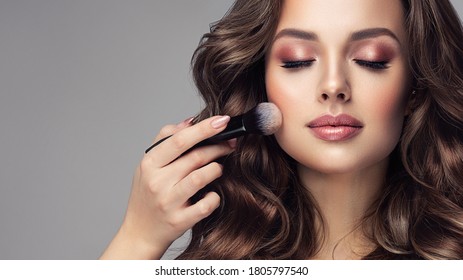 Makeup artist applies   applies powder and blush  . Beautiful woman face. Hand of make-up master puts blush on cheeks  beauty  model girl . Make up in process