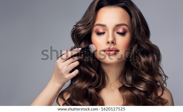 Makeup artist applies   applies powder
and blush  . Beautiful woman face. Hand of make-up master puts
blush on cheeks  beauty  model girl . Make up in
process