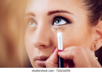 Makeup Artist Applying Concealer On A Beautiful Young Woman's Face. Close Up.