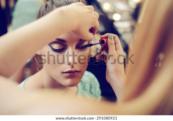 Make-up\
artist applying the mascara to model. Close up.\
