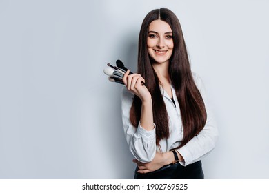 Makeup artist with brushes in hand on a white background