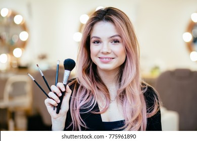 Makeup Artist With Brushes In Hand On A Blurred Background.