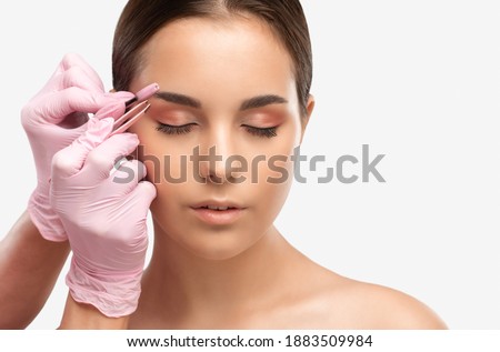 Makeup artist combs  and plucks eyebrows after dyeing in a beauty salon.Professional makeup and cosmetology skin care.