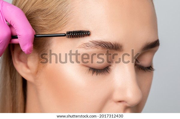 Makeup artist combs  and plucks eyebrows after\
dyeing in a beauty salon.Professional makeup and cosmetology skin\
care.