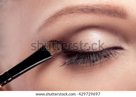 makeup artist deals makeup brush for eyes. makeup for a young beautiful girl. brown eye shadow. close up
