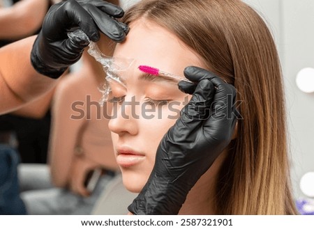 The make-up artist does Long-lasting styling of the eyebrows of the eyebrows and will color the eyebrows. Eyebrow lamination. Professional make-up and face care.