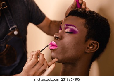 Makeup artist doing makeup on an African transgender person. - Powered by Shutterstock