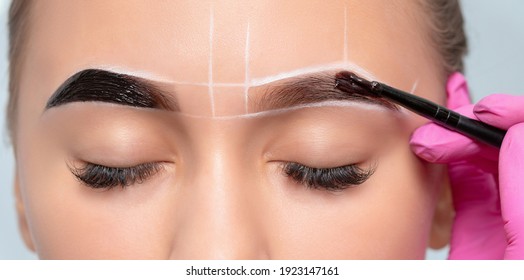Make-up artist makes markings with white pencil for eyebrow and paints eyebrows. Professional makeup and facial care. - Shutterstock ID 1923147161