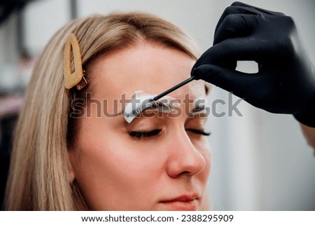 The makeup artist performs long-term eyebrow styling and paints the eyebrows. Lamination of eyebrows. Professional makeup and facial care. Makes markings for permanent makeup.