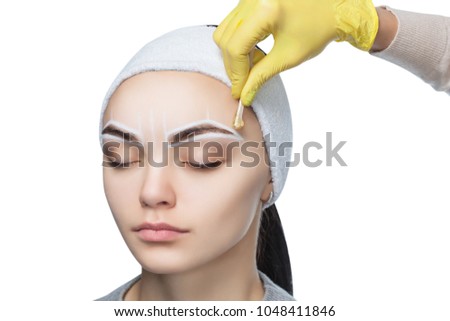 The make-up artist plucks her eyebrows, before the procedure of permanent make-up in the beauty salon.