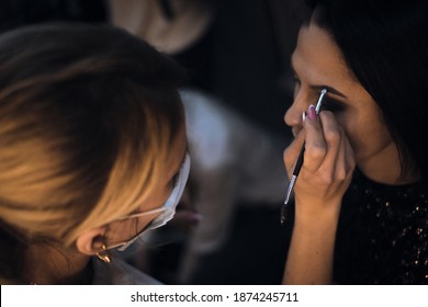 Make-up Artist In A Protective Mask Paints A Young Girl For A Gala Event. Woman Makes Make-up For The Bride In Quarantine On Isolation