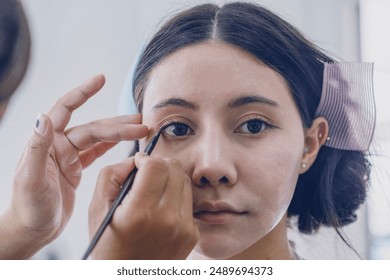 makeup artist used an eyebrow pencil to draw the lower eyelids of an Asian female model and used makeup to cover her lips. - Powered by Shutterstock