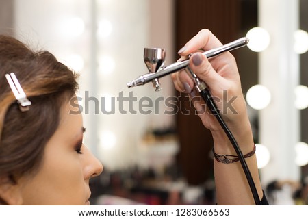 Makeup artist using airbrusher.