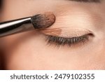 makeup artist using makeup brush for eyes and applying brown eyeshadow. make-up for young asian girl. Close-up
