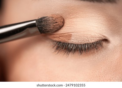 makeup artist using makeup brush for eyes and applying brown eyeshadow. make-up for young asian girl. Close-up