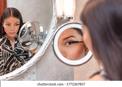 Make-up Asian Woman Getting Ready For Work Applying Makeup Mascara In Magnifying Beauty Mirror At Home. Beautiful Businesswoman Looking In Mirror In Bathroom. Morning Routine Before Going To Work.