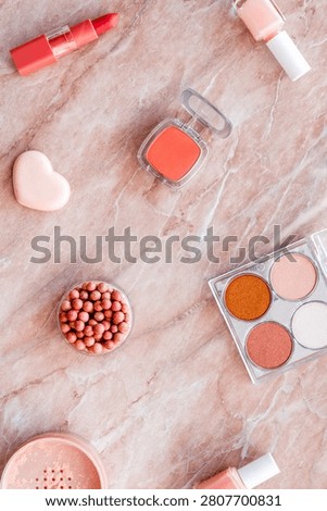 Makeup background with rounge, powder and tools on light brown table top view.