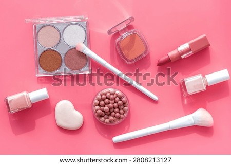 Makeup background with rounge, powder and tools on pink table top view.