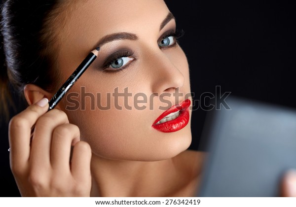 Make-up. Beautiful Woman Doing Makeup Eyebrow Pencil.\
Red Lips 