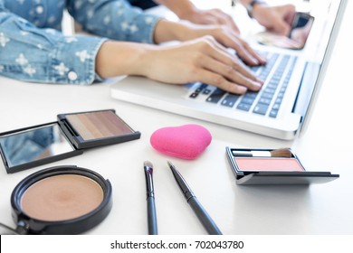 Makeup and beauty blog, elegant female fashion blogger working with a laptop, many cosmetics and teaching online tutorial.