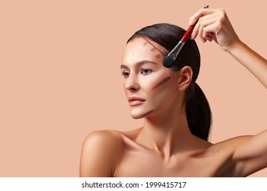 Makeup beauty. Portrait of a beautiful young woman brunette with smooth skin and fresh makeup. Applying  makeup product, contouring and highlighting lines of cheekbones and chin. Makeup angle of youth - Shutterstock ID 1999415717