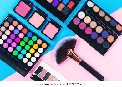 Makeup And Beauty Products On Pink And Blue Background. Eye Shadow Palettes. Fan Contouring Brush And Blushes. Flatlay, Top View. 