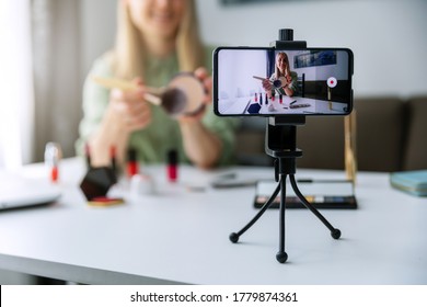 makeup blogger influencer recording tutorial video with phone for social media at home