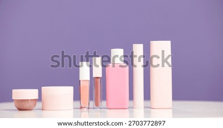 Makeup, bottles and product selection in studio for beauty aesthetic, skincare routine and marketing. Space, container or cosmetic range for dermatology, wellness or advertising on purple background.