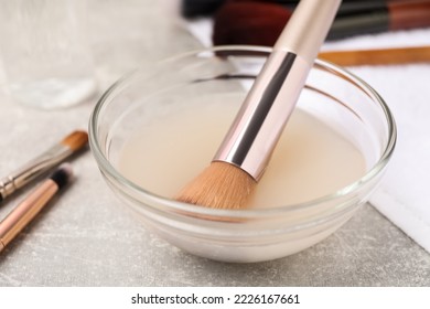 Makeup brush in bowl with cleanser on grey table, closeup - Powered by Shutterstock