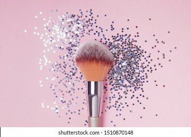 Make-up brush and star shaped confetti on pink backround, top view. Perfect makeup concept.