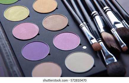 Makeup brushes and make-up eye shadows on desk