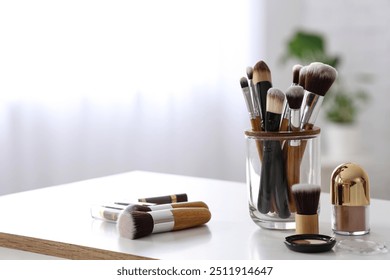 Makeup brushes and eyeshadows on white table at home