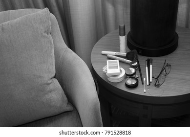 makeup, brushes and glasses on a table next to a chair