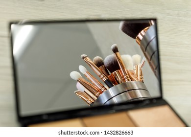 makeup brushes are reflected in a palette mirror with shadows.