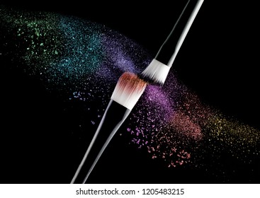 Makeup brushes splashing colorful particles isolated black background