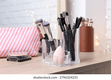 Makeup brushes and sponge in holder on wooden vanity indoors