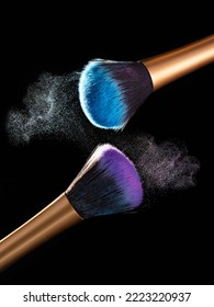 Makeup Concept. Stop Action View Of Two Makeup Brushes Applying Matching Red And Gold Powder Over Black Background