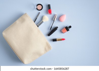 Make-up cosmetic bag on blue background. Stylish makeup artist pouch with beauty products. Flat lay, top view - Shutterstock ID 1645856287